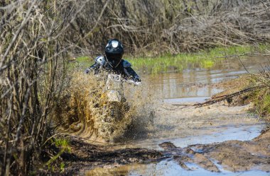 Enduro motorcycle rides through the mud with a big splash