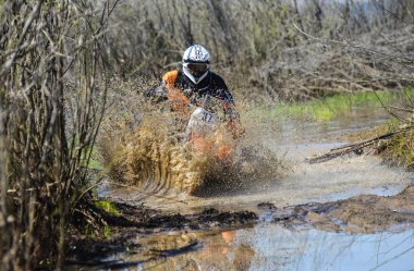Enduro motorcycle rides through the mud with a big splash