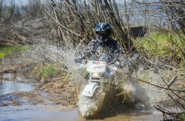 Enduro motorcycle rides through the mud with a big splash