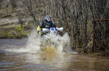 Enduro motorcycle rides through the mud with a big splash