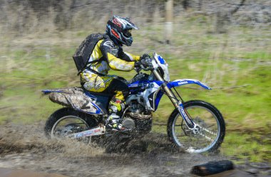 Enduro motorcycle rides through the mud with a big splash