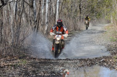 Enduro motorcycle rides through the mud with a big splash