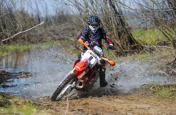 Enduro motorcycle rides through the mud with a big splash — Stockfoto