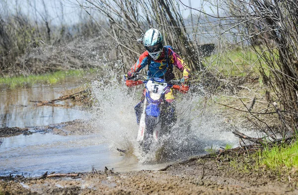 Enduro motorcycle rides through the mud with a big splash