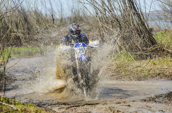 Enduro motorcycle rides through the mud with a big splash — Stockfoto