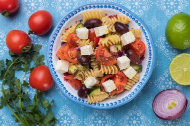 Bir kase peynirli salata, fusili makarna ve taze sebze.