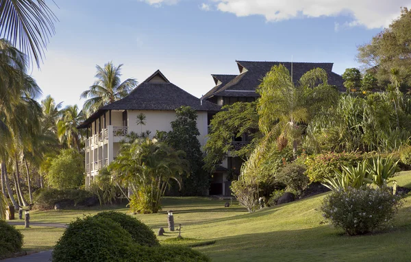 Standard buildings of the tropical settlement among foliage — Stock Photo, Image