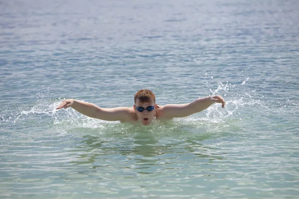 Young sporting man swims in the sea butterfly stroke style. — Stock Photo, Image