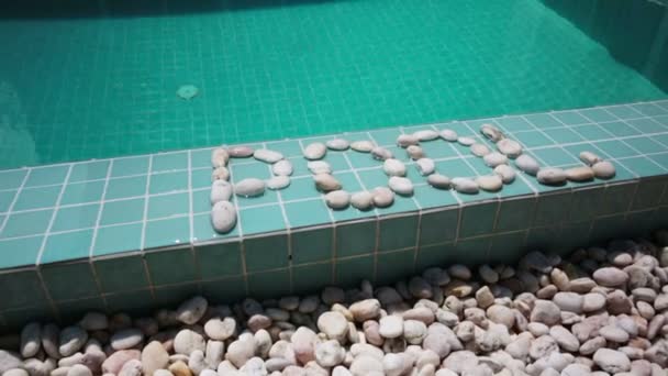 Inskriften poolen är anlagd av sten på en pool sida — Stockvideo