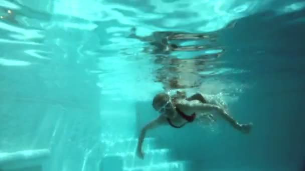 La jeune belle femme aux cheveux longs nage dans la piscine sous l'eau — Video