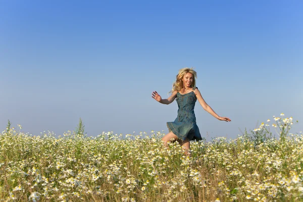 The happy young woman jumps in the field  of camomiles — Stock Photo, Image