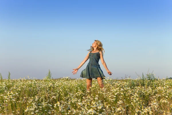 The happy young woman jumps in the field  of camomiles — Stock Photo, Image