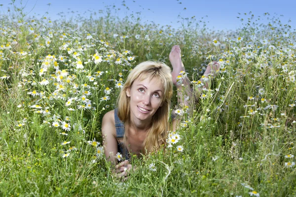 Прекрасная счастливая молодая женщина лежит в поле ромашки — стоковое фото