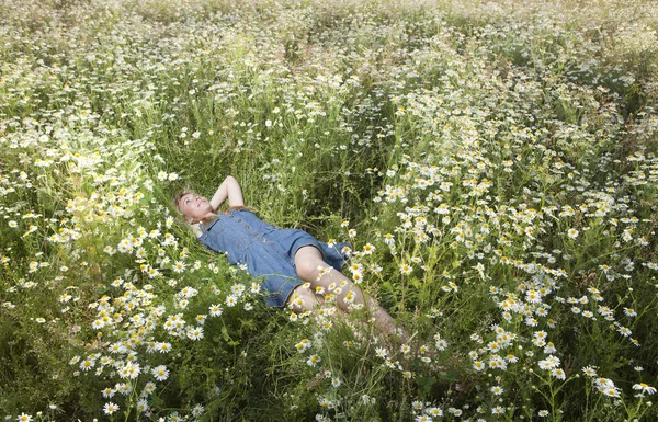 Krásná šťastná mladá žena leží v oblasti Heřmánek — Stock fotografie