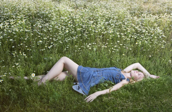 The beautiful happy young woman lies in the field of chamomile — Stock Photo, Image