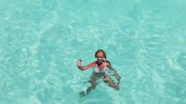 De gelukkige vrouw in de golven van de zee voor ons een hand groet — Stockvideo