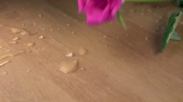 Rose rouge dans des éclaboussures d'eau tombe sur une table en bois, au ralenti — Video