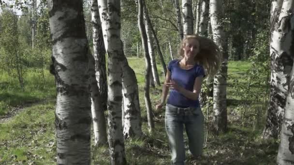 A bela mulher jovem corre na madeira de vidoeiro — Vídeo de Stock