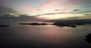 Hava aracı görüntüsü, deniz ve dağlık adalar üzerinde dramatik günbatımı, gökyüzünde bulutlar. Lombok, Endonezya yakınlarındaki küçük Gili Asahan adasından görüntü