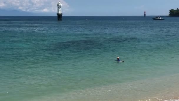 Молодая стройная женщина купается в голубом море в тропическом курорте, Ломбок Индонезия — стоковое видео