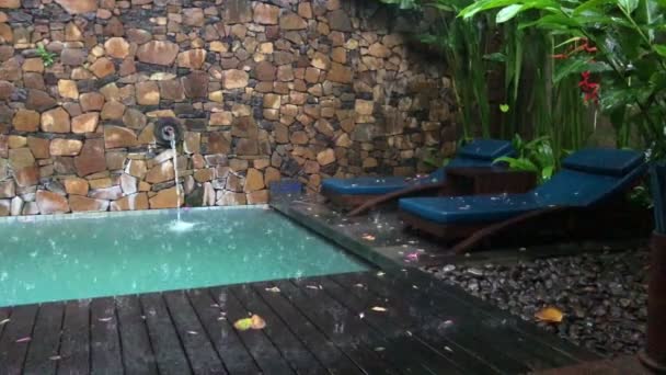 リゾートでの熱帯雨林、雨滴がプールとサンラウンジャーに滴り落ちる — ストック動画