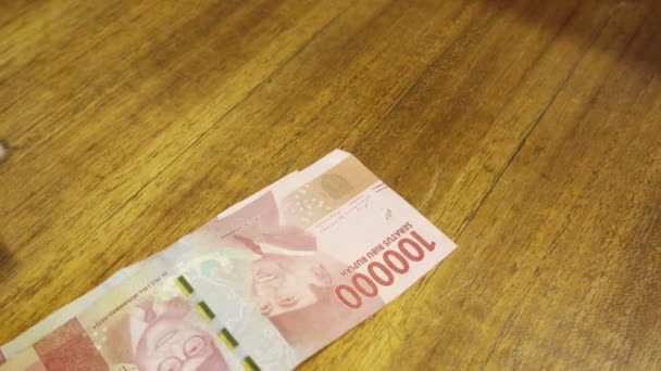 Руки пересчитываются и кладутся на стол индонезийской рупии — стоковое видео