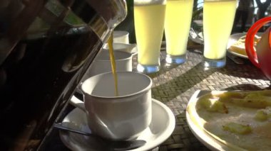 Sütlü kahve, meyve suyu ve tropik bir otelde kahvaltının arka planına dökülür.