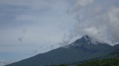 Rüzgardan hareket eden bulutlar volkanın tepesine yakın, zaman ayarlı. Güneşli bir günde mavi gökyüzü