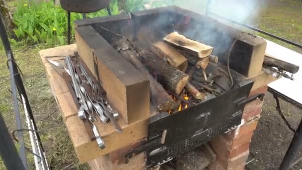 Brûlures de bois dans une mangale de rue près d'une maison de campagne, Préparation pour la cuisson sur un feu ouvert, Shashlyk, saucisses, barbecue — Video