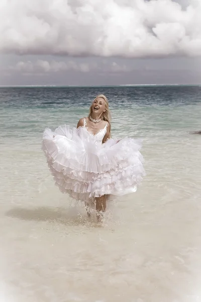 La bella donna giovane in un vestito della sposa corre su onde del mare — Foto Stock