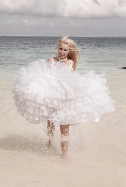 La mujer joven hermosa en el vestido de la novia corre sobre las olas del mar — Foto de Stock
