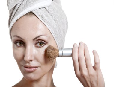 Makyaj için fırçası olan havluyla güzel genç bir kadın.