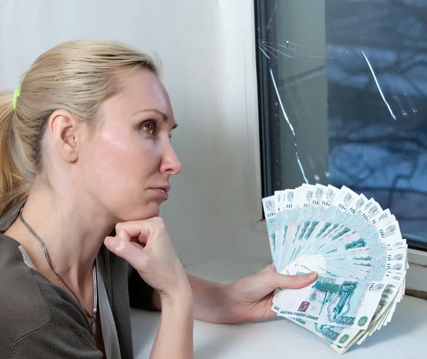 The housewife upset and counts money for repair of a window which has burst in a frost — Stock Photo, Image