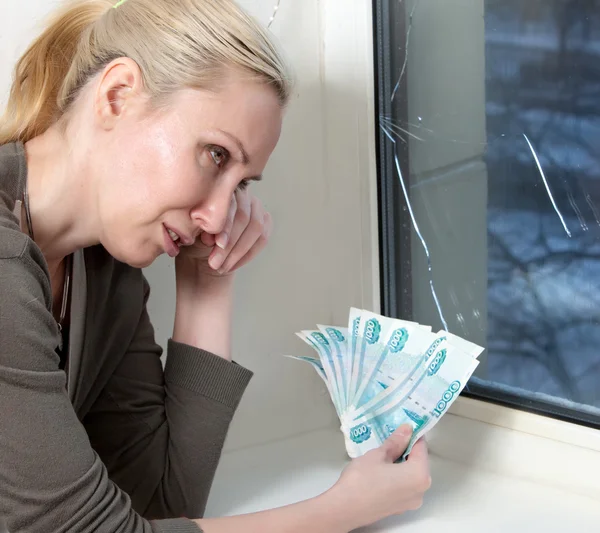 Die Hausfrau verärgert und zählt das Geld für die Reparatur des Fensters, das im Frost geplatzt ist — Stockfoto