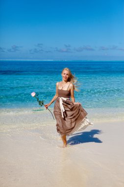 Bir plajda denizin kenarında güzel kadın bir gül ile çalışır. Polinezyası