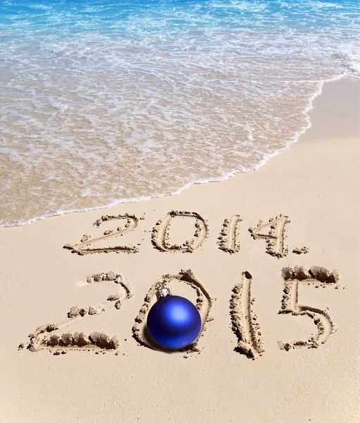 Sur le sable, il est écrit 2014 et 2015 et la balle du Nouvel An se trouve — Photo