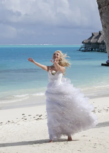 De jonge mooie vrouw in een jurk van de bruid aan rand van de zee — Stockfoto