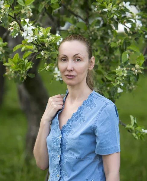 Jovem mulher atraente em pé perto da macieira florescente — Fotografia de Stock