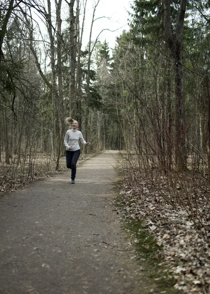 The woman runs on the track in the spring wood — Stock Photo, Image