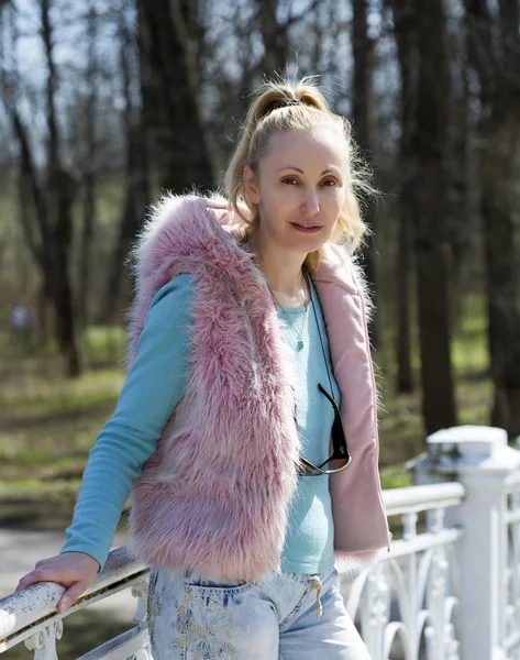 The young woman in bright clothes on the bridge in park in the early spring — Stock Photo, Image