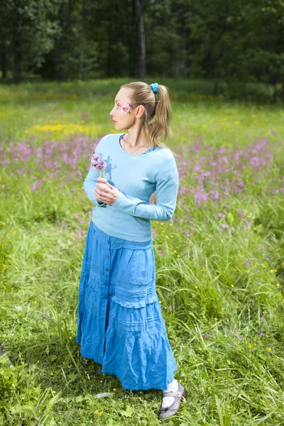 Mutlu genç kadın, kır çiçekleri alanında — Stok fotoğraf