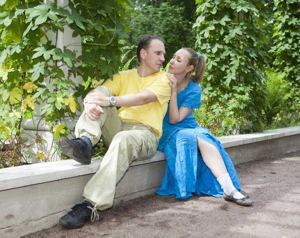 Boldog a fiatal pár ül a kerti pavilon sodrott zöldek — Stock Fotó