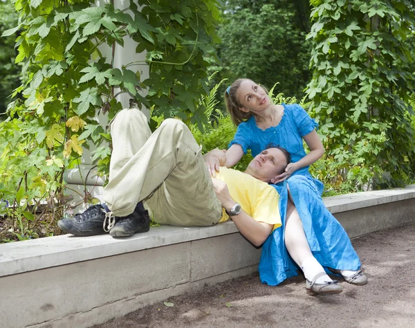 Young happy couple sits in the arbour twined greens — Stock Photo, Image