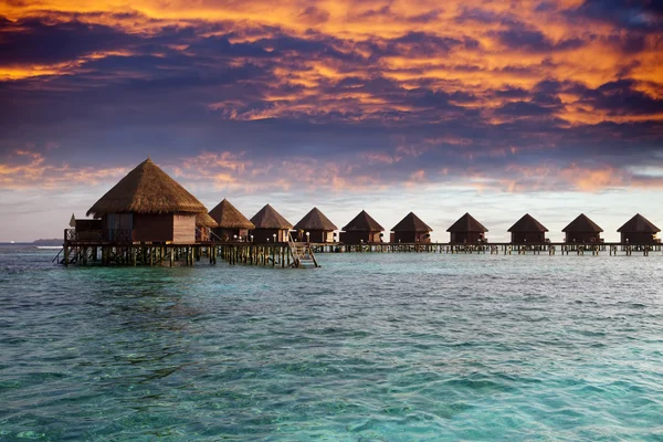 Hütten über Wasser zum Zeitpunkt des Sonnenuntergangs. Malediven — Stockfoto