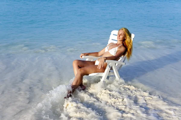 Jovem mulher bonita em uma cadeira de praia no mar — Fotografia de Stock