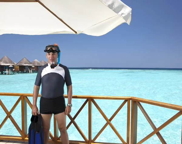 Ο άνθρωπος του αθλητισμού σε ένα κοστούμι για ένα ψαροντούφεκο στο χώρο ηλιοθεραπείας του ένα σπίτι πάνω από τη θάλασσα. Μαλδίβες — Φωτογραφία Αρχείου