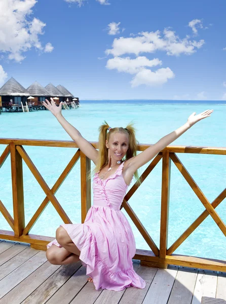 Junges schönes Mädchen steht in pinkfarbener Uniform auf dem Sonnendeck einer Villa am Wasser, Malediven — Stockfoto