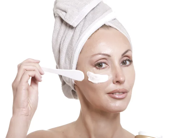 De mooie jonge vrouw in de handdoek met een cosmetische crème — Stockfoto