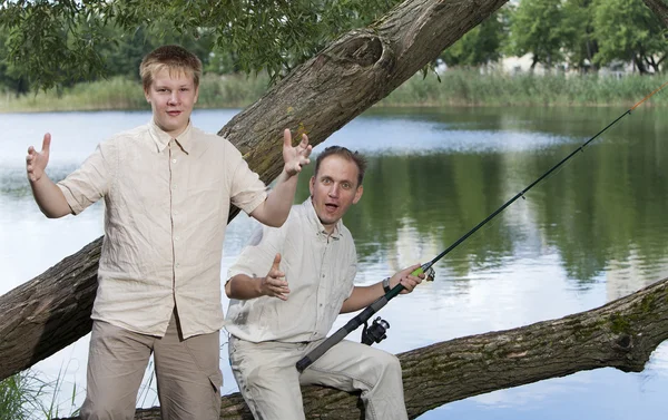 El padre con el hijo en la pesca, muestra el tamaño de los peces — Foto de Stock