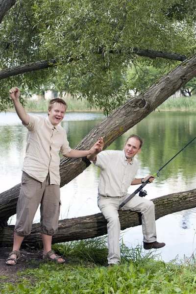Отец с сыном на рыбалке, показывает размер рыбы — стоковое фото